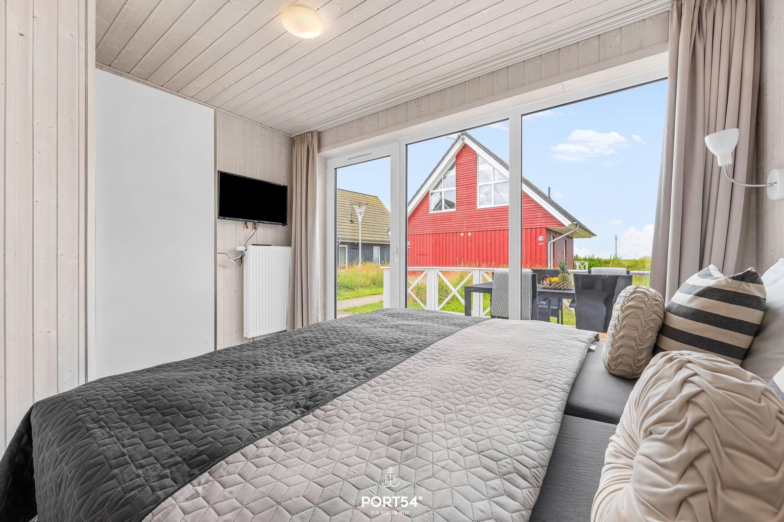 Schlafzimmer mit Blick auf rotes Haus und Terrasse