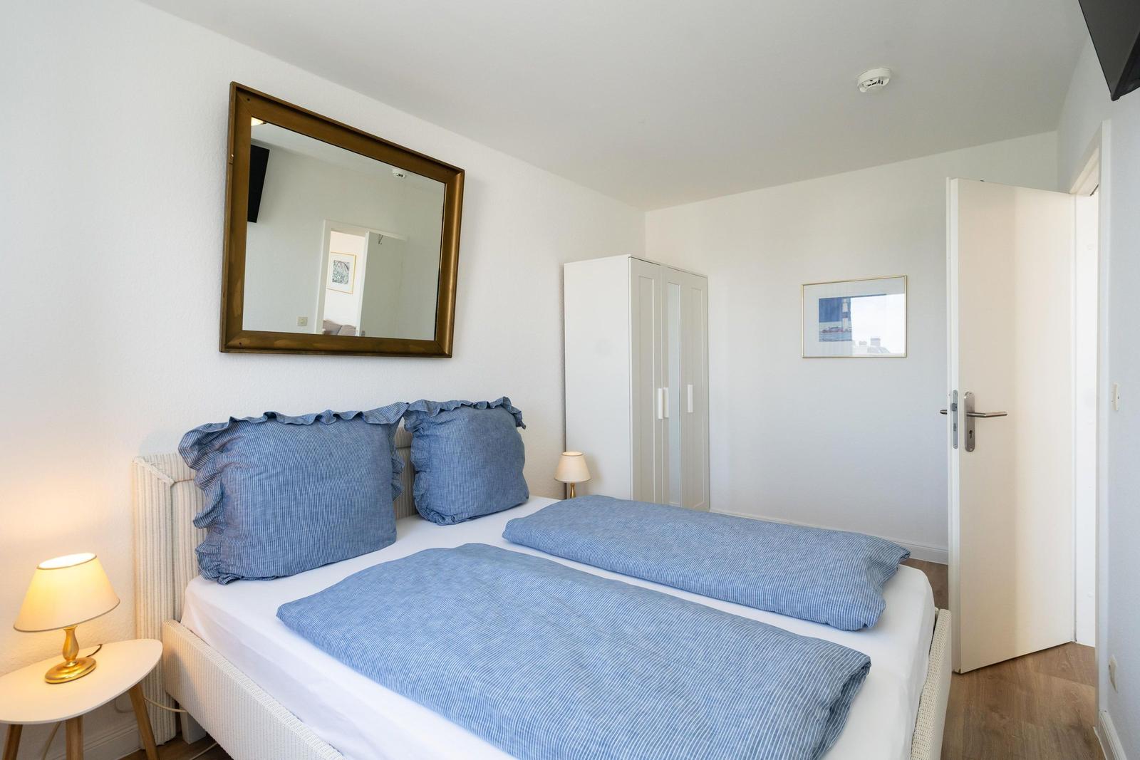 Schlafzimmer mit Bett, Spiegel und Kleiderschrank