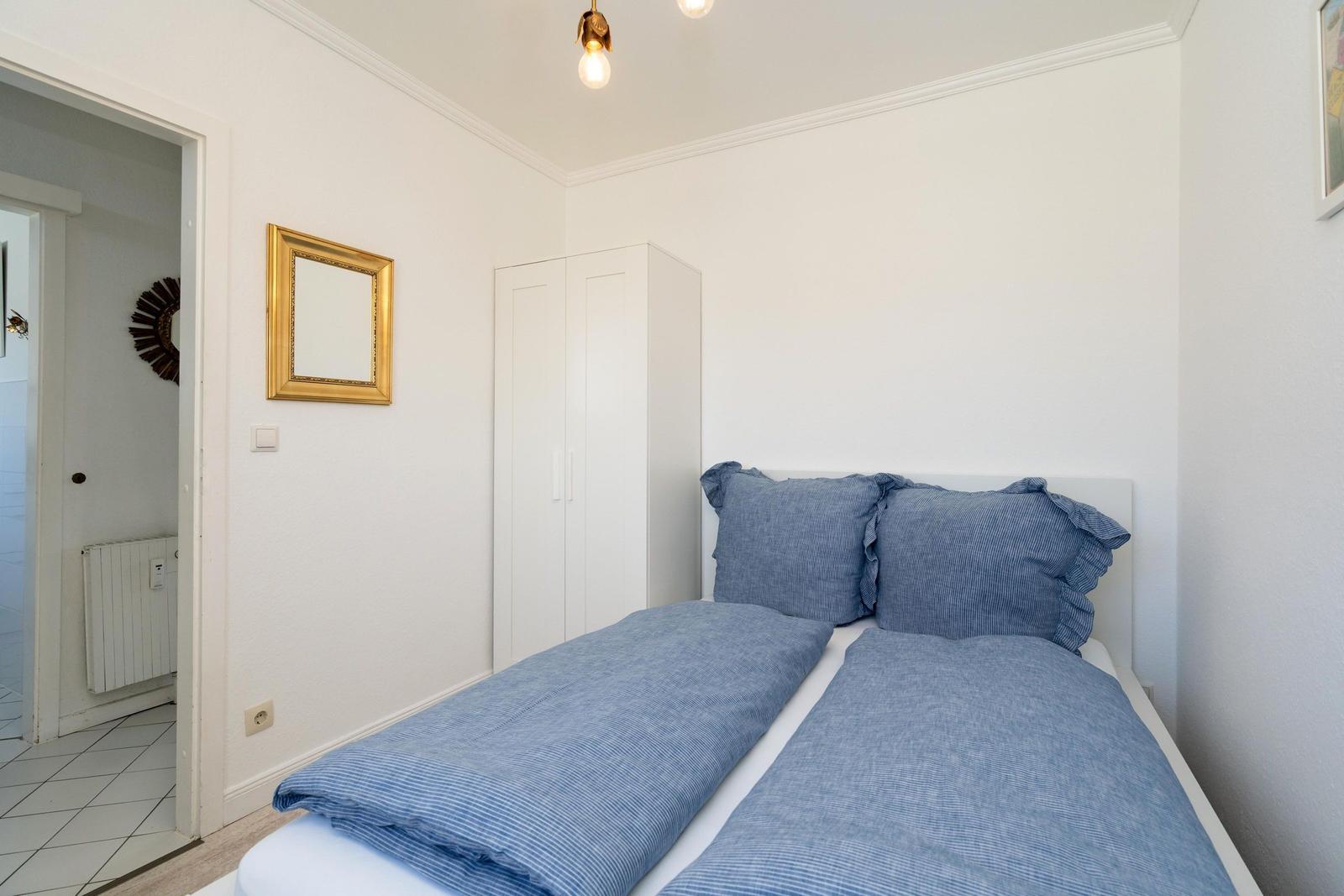 Schlafzimmer mit Bett, Kleiderschrank und Spiegel an der Wand.