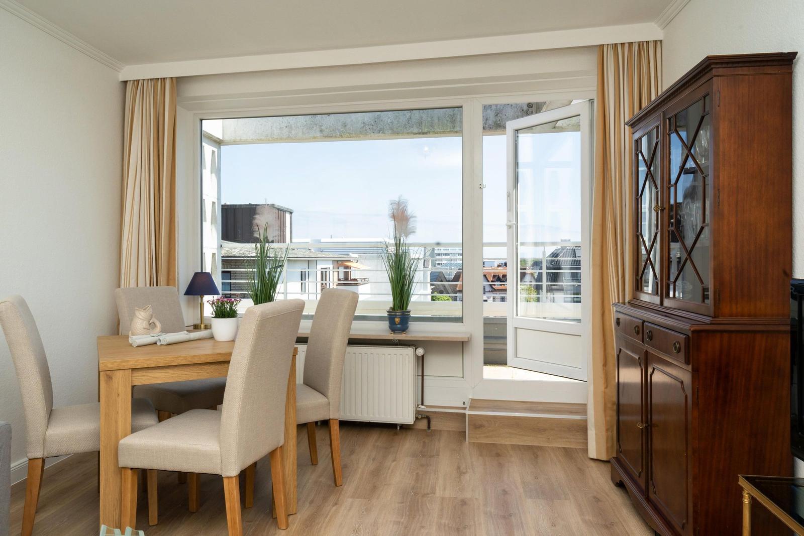Esszimmer mit Tisch, Stühlen und Blick auf Balkon. Holzfußboden und hölzerner Schrank.