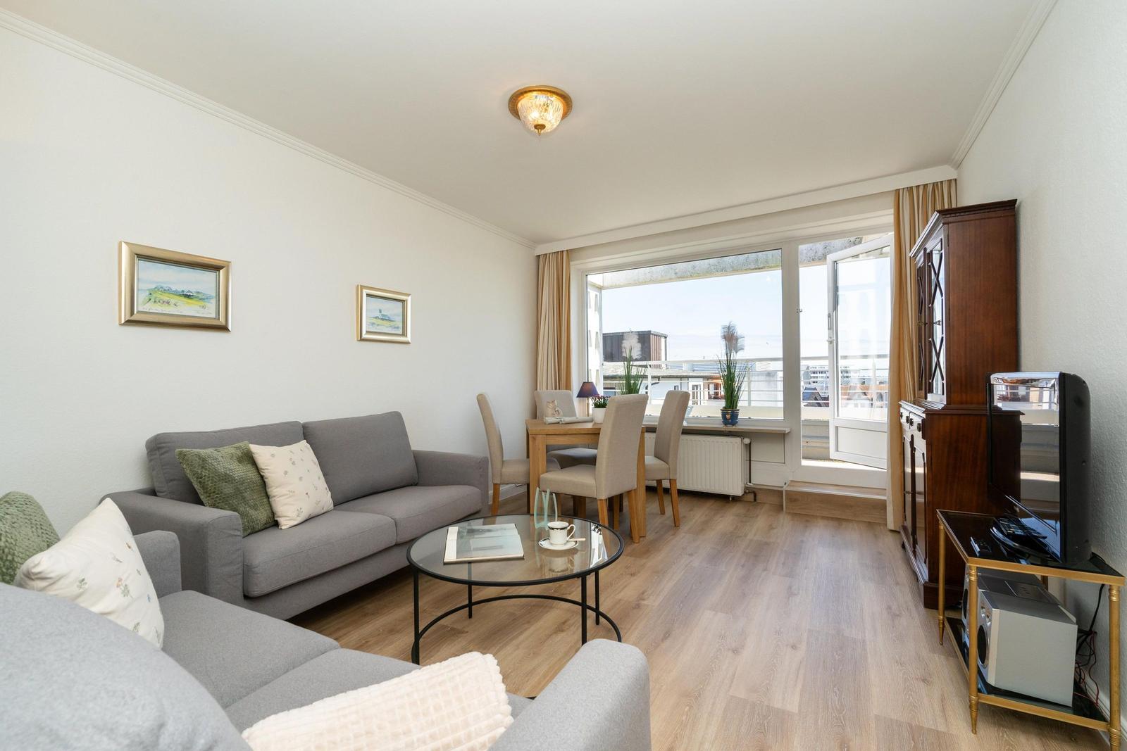 Wohnzimmer mit Sofa, Esstisch und Blick auf Balkon