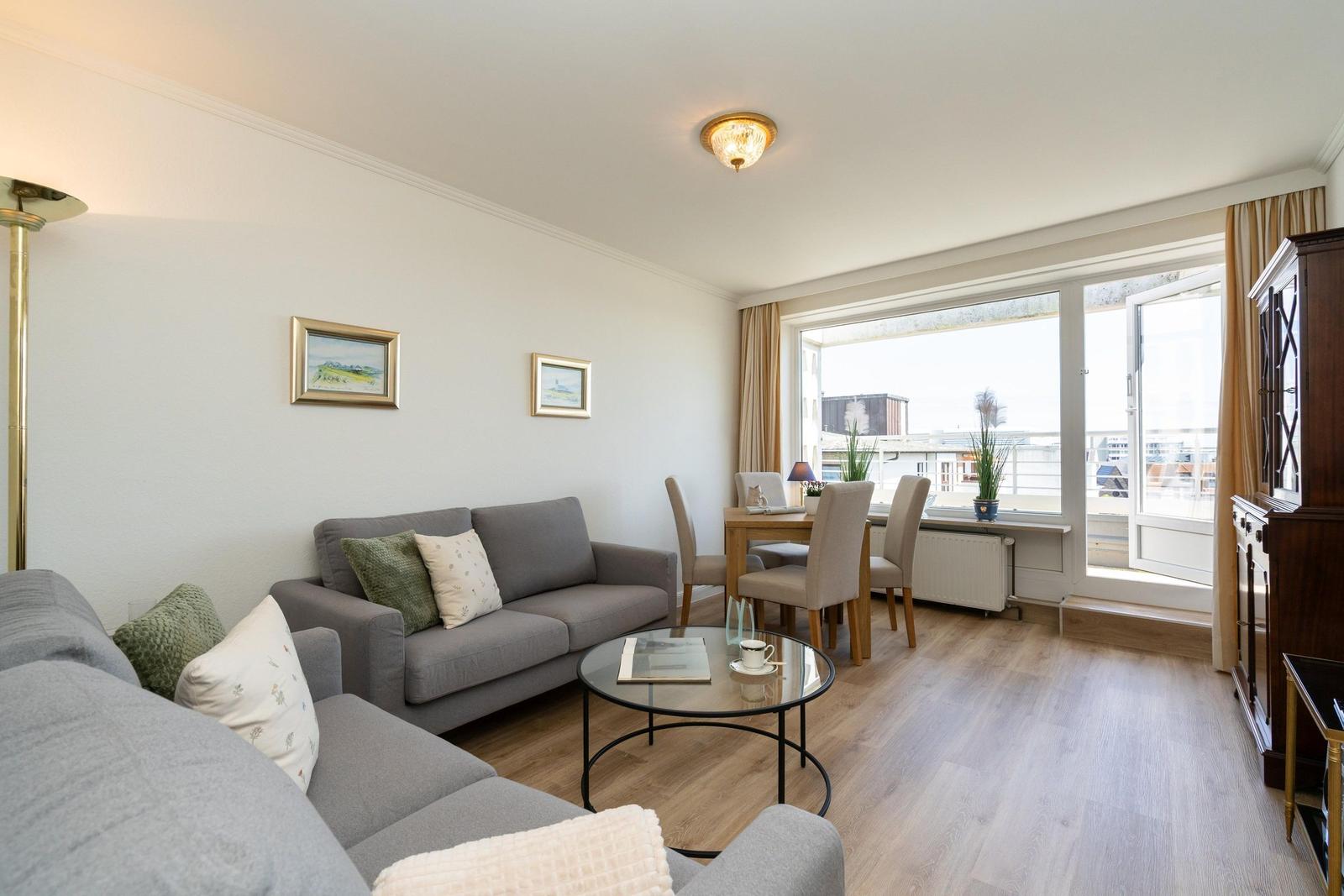 Wohnzimmer mit Sofa, Esstisch und Blick auf Balkon.