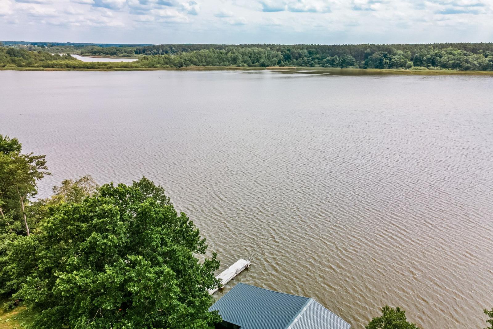 Haus mit Bootsanlegestelle am See, umgeben von Wald und Wasser.