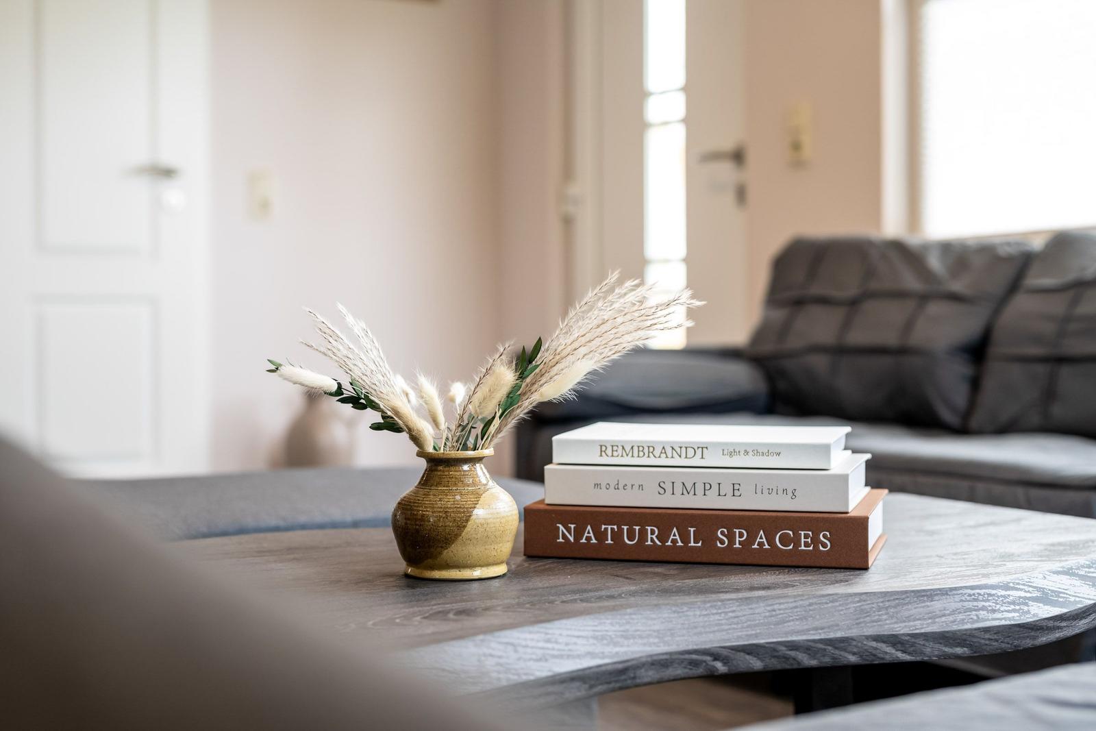Tisch mit Vasen und Büchern vor einem Sofa