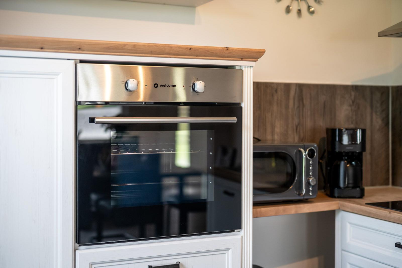 Küche mit eingebautem Backofen, Mikrowelle und Kaffeemaschine.