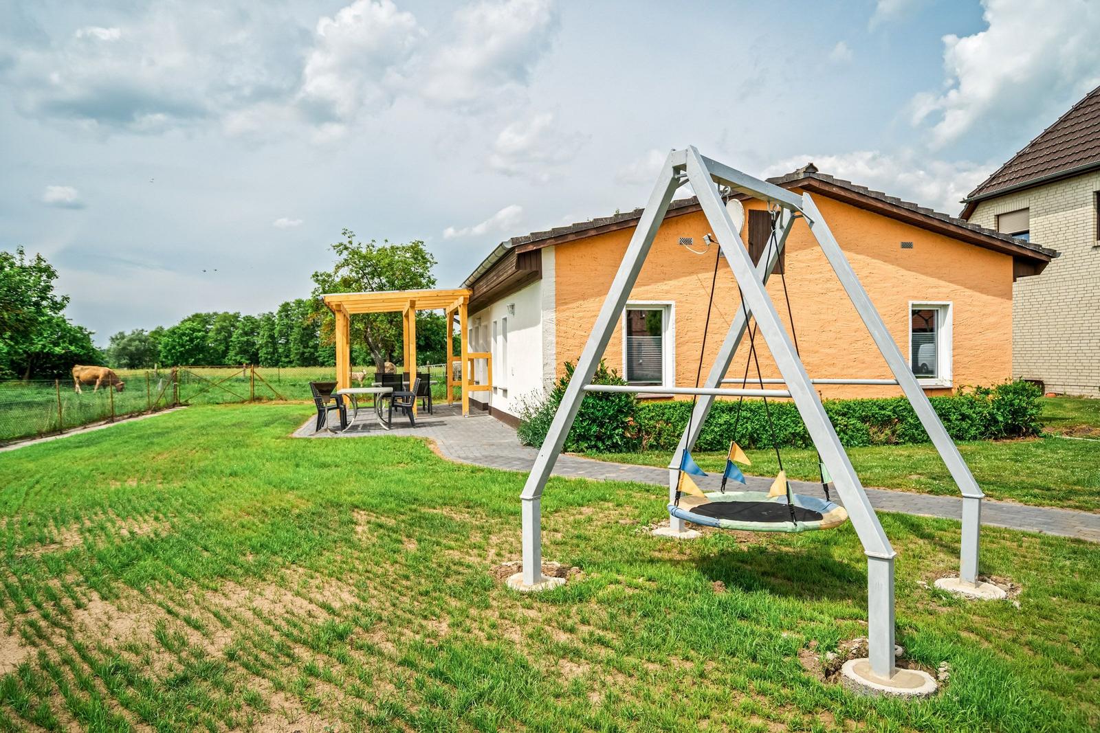 Haus mit Garten, Trampolin und Terrasse mit Tisch und Stühlen.