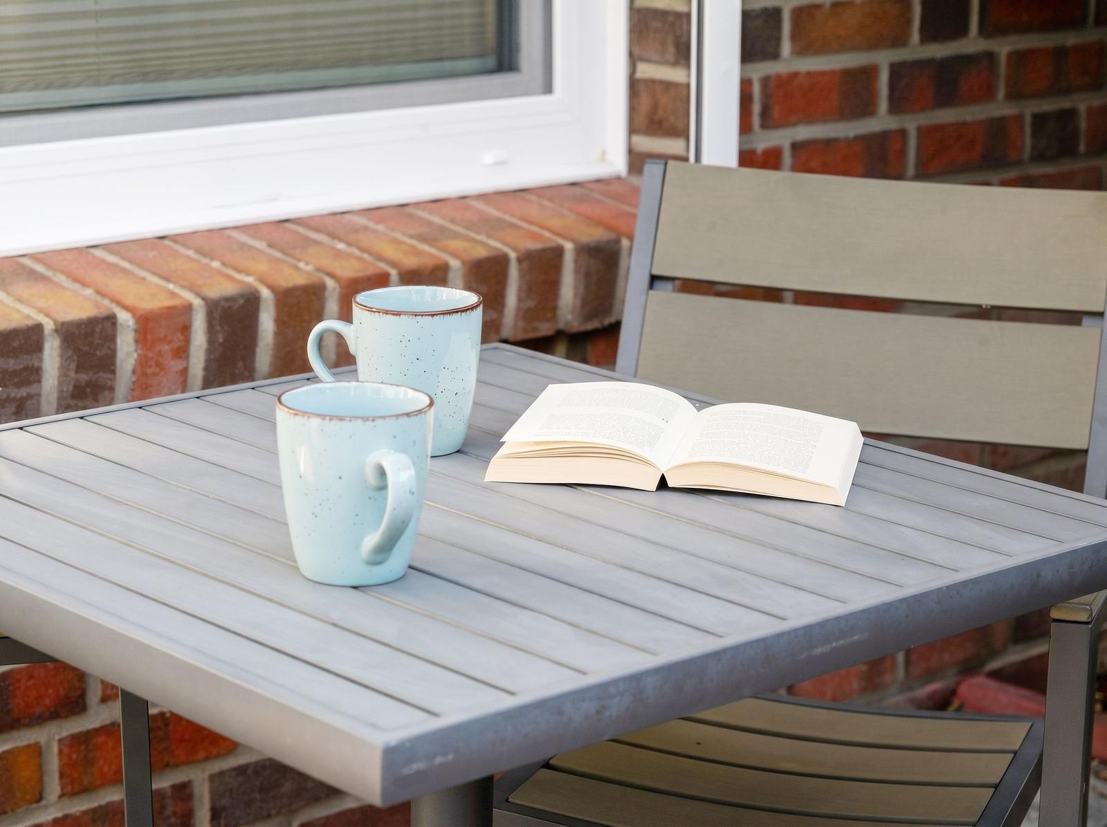 Auf dem Balkon steht ein Tisch mit zwei Tassen und einem Buch.