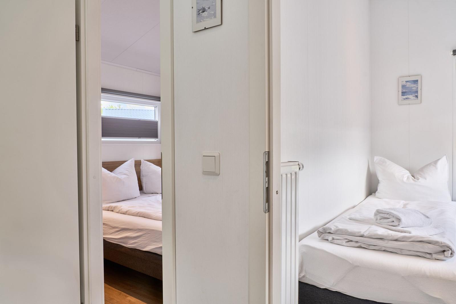 Zwei Schlafzimmer mit Betten und Fenstern. Ein Raum hat einen Heizkörper.