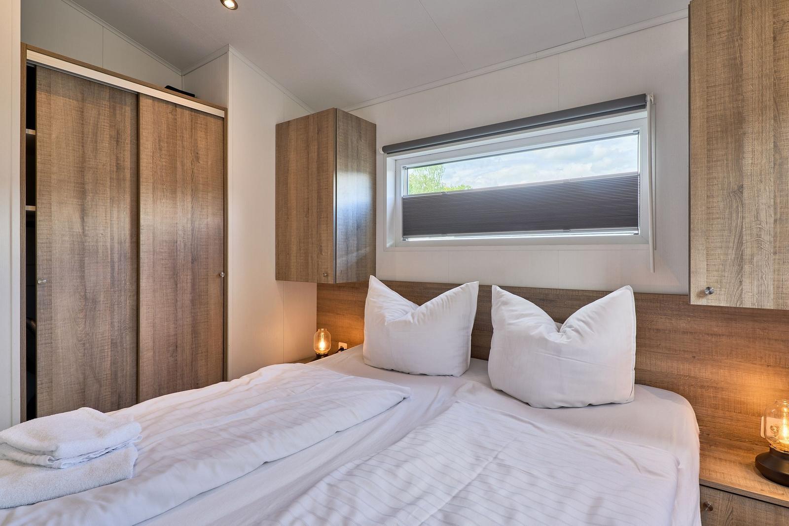 Schlafzimmer mit Doppelbett, Holzmöbeln und Fenster mit Blick.