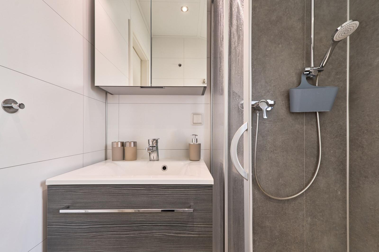 Badezimmer mit Waschbecken, Spiegel und Dusche