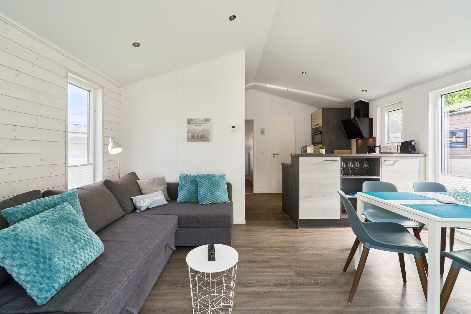 Wohnzimmer mit Sofa, Esstisch und Küchenbereich