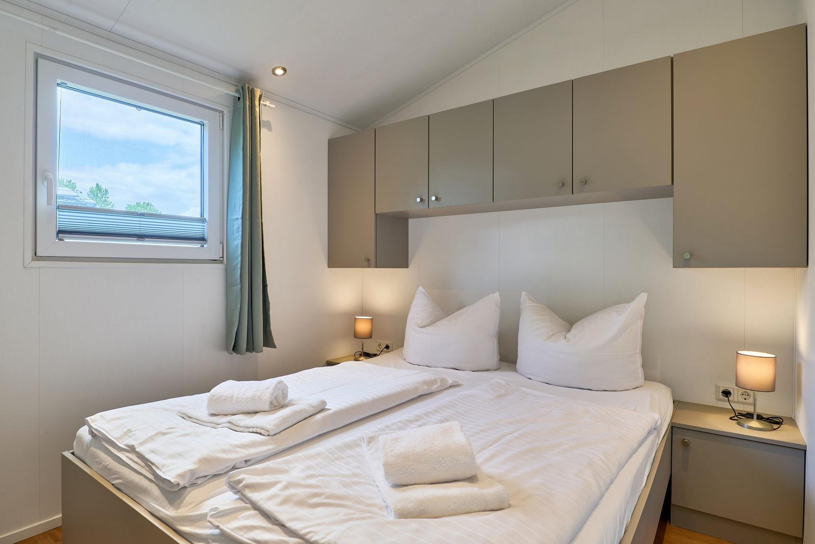 Schlafzimmer mit Doppelbett, Nachttischen und Fenster mit Blick.