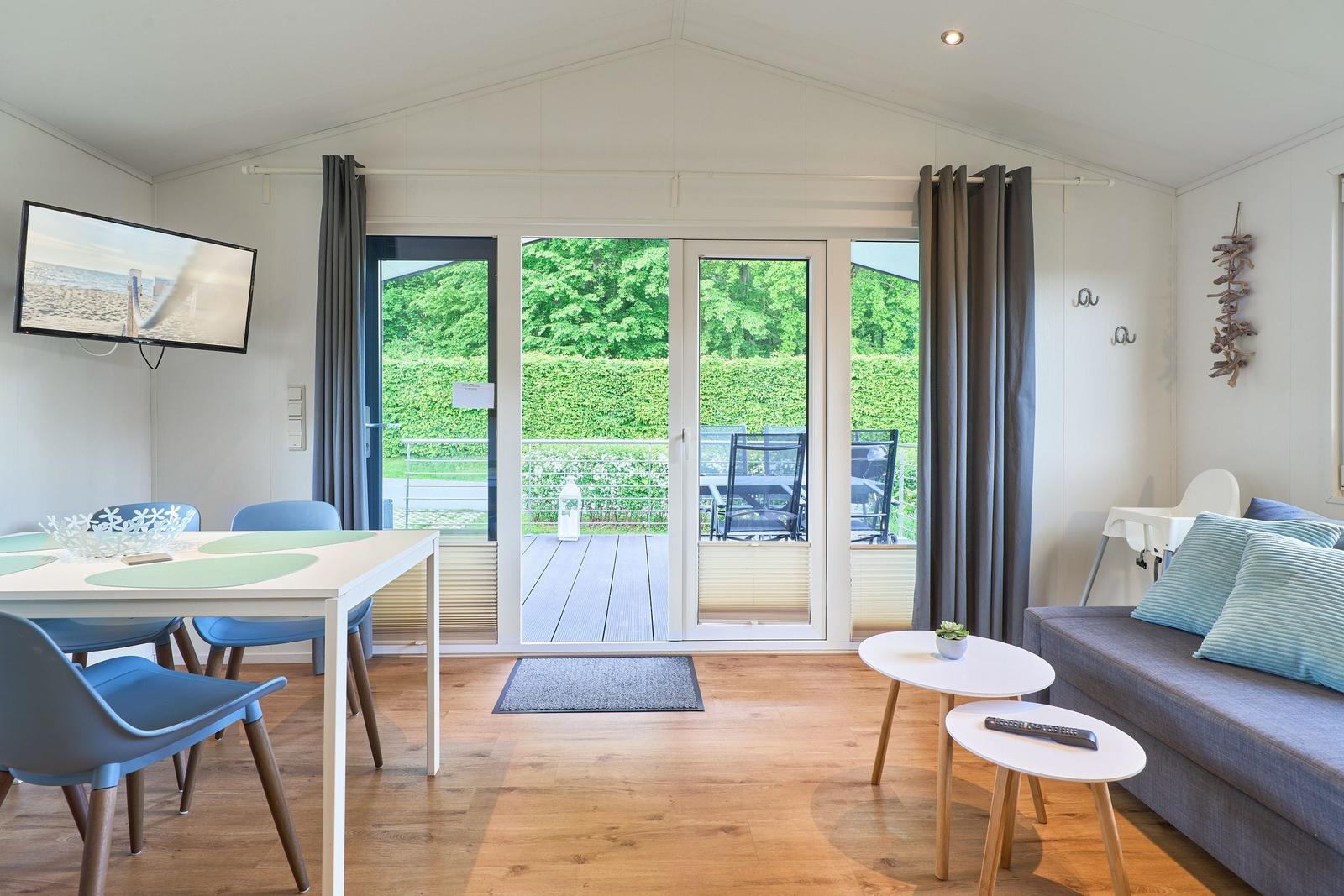 Wohn- und Essbereich mit Balkon, TV und Holzboden.