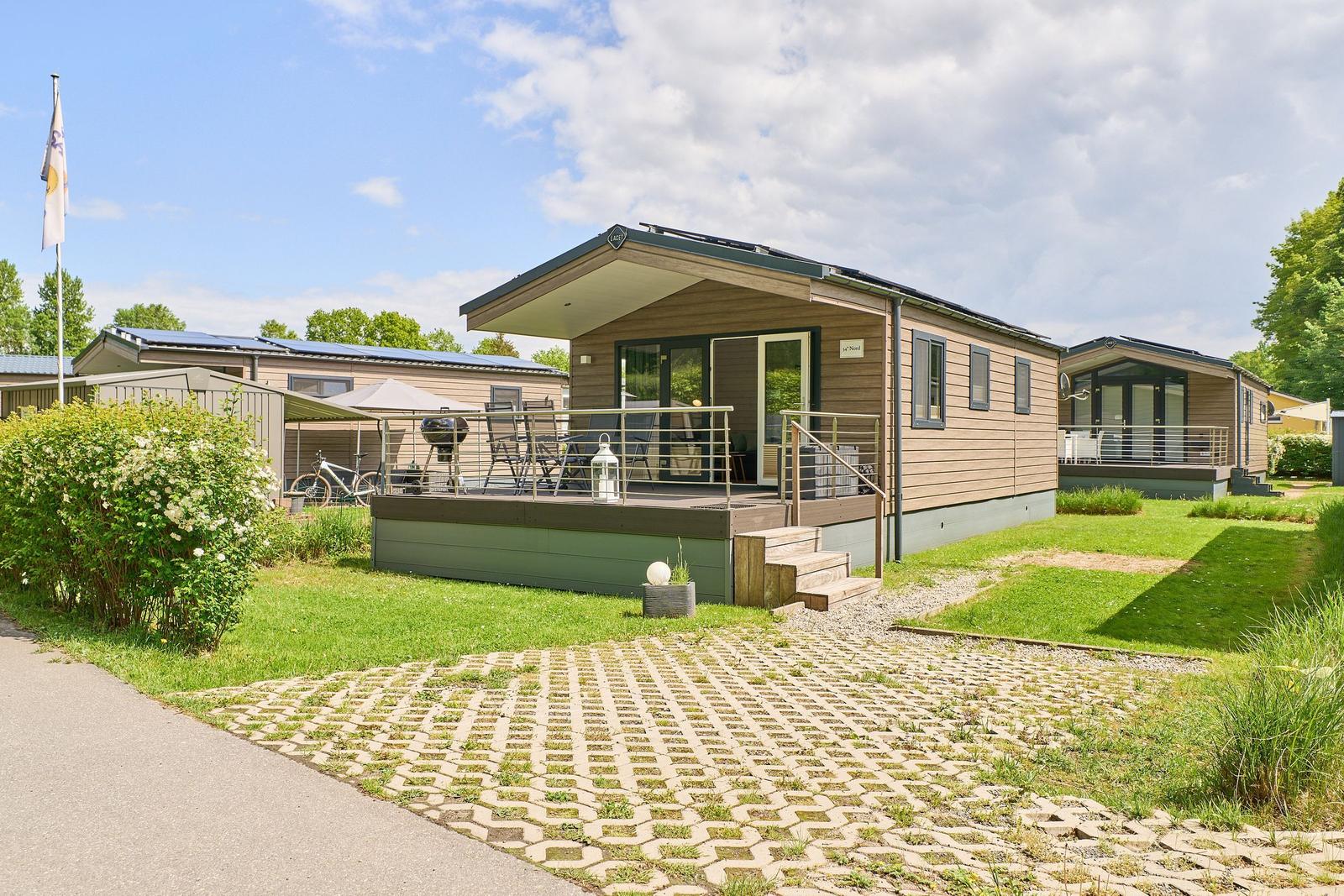 Mobile Home mit Terrasse, Grill und Garten. Modernes Design mit Holzfassade und Glasfront.