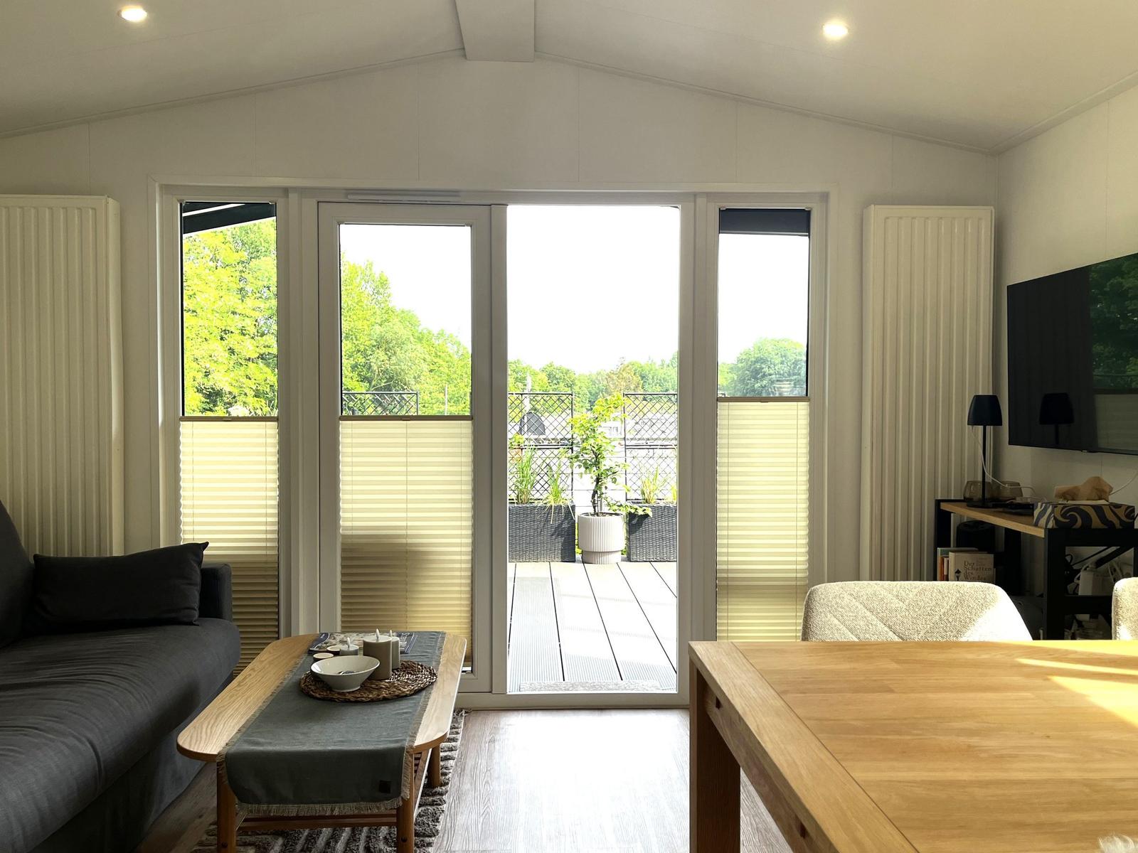 Wohnraum mit Blick auf Balkon, Sofa, Esstisch und Fernseher
