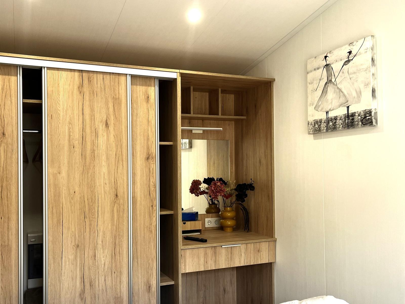 Schlafzimmer mit Holzschrank, Spiegelfläche und Wandbild