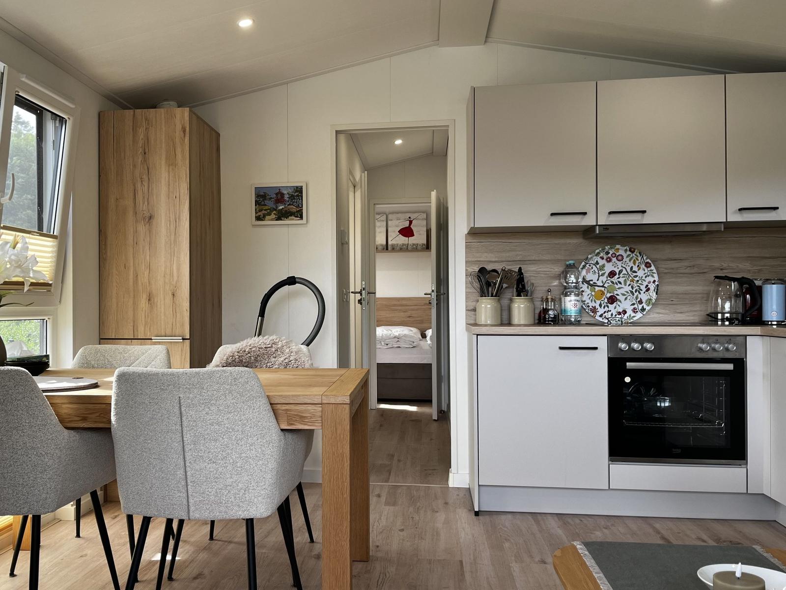 Küche mit Essbereich und Blick in Schlafzimmer. Holzmöbel und moderne Geräte.