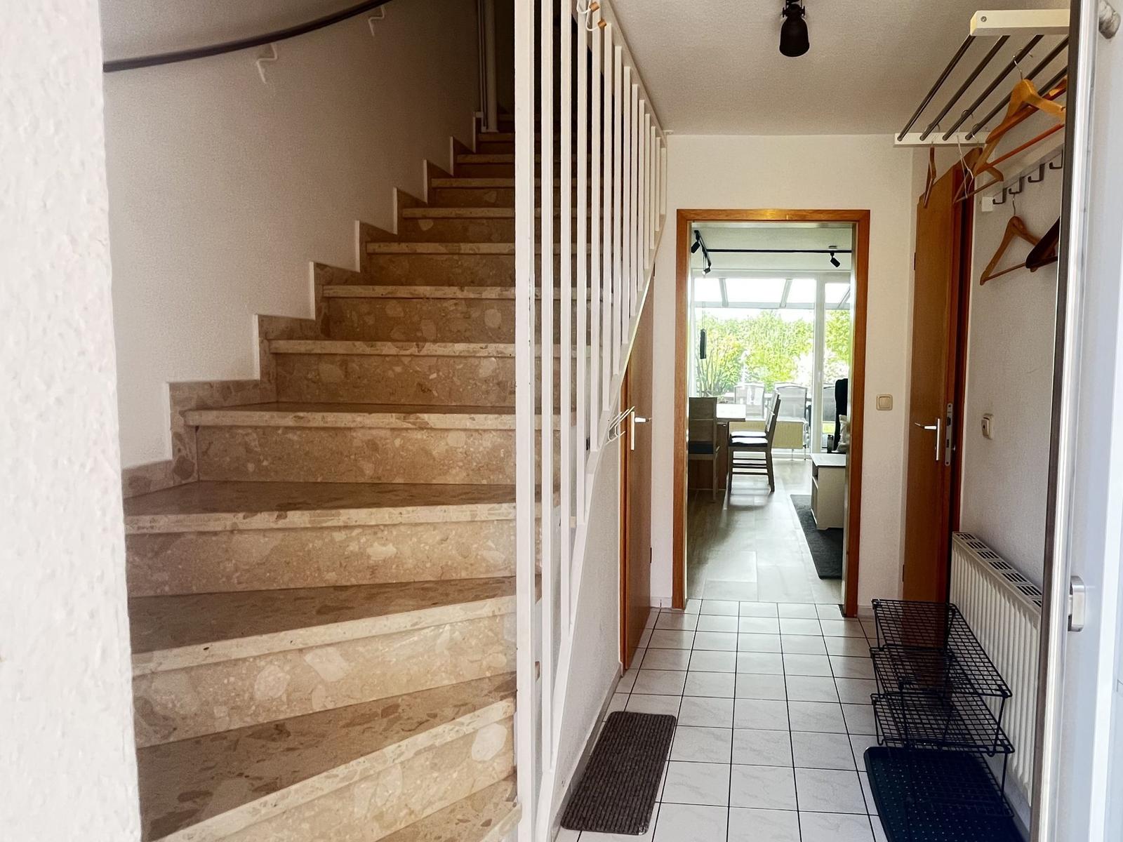 Hausflur mit Stein-Treppe, Fliesenboden und Blick in Essbereich.