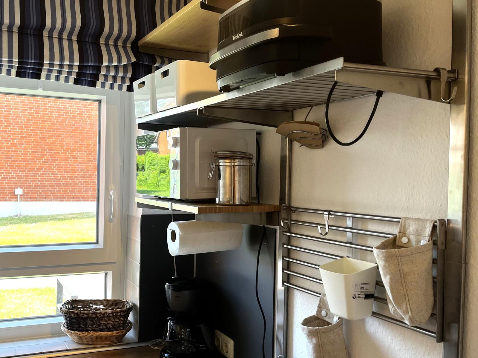 Küchenbereich mit Fenster, Mikrowelle, Tefal-Bratentherm und Kaffeemaschine.