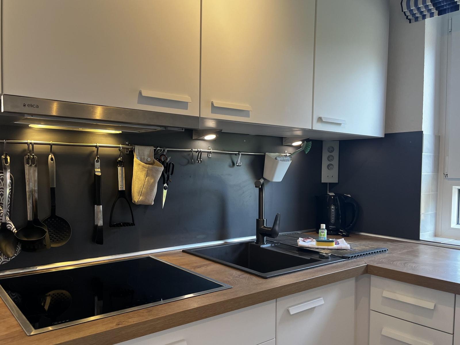 Küche mit Spüle, Herd und Hängeschürzen an der Wand