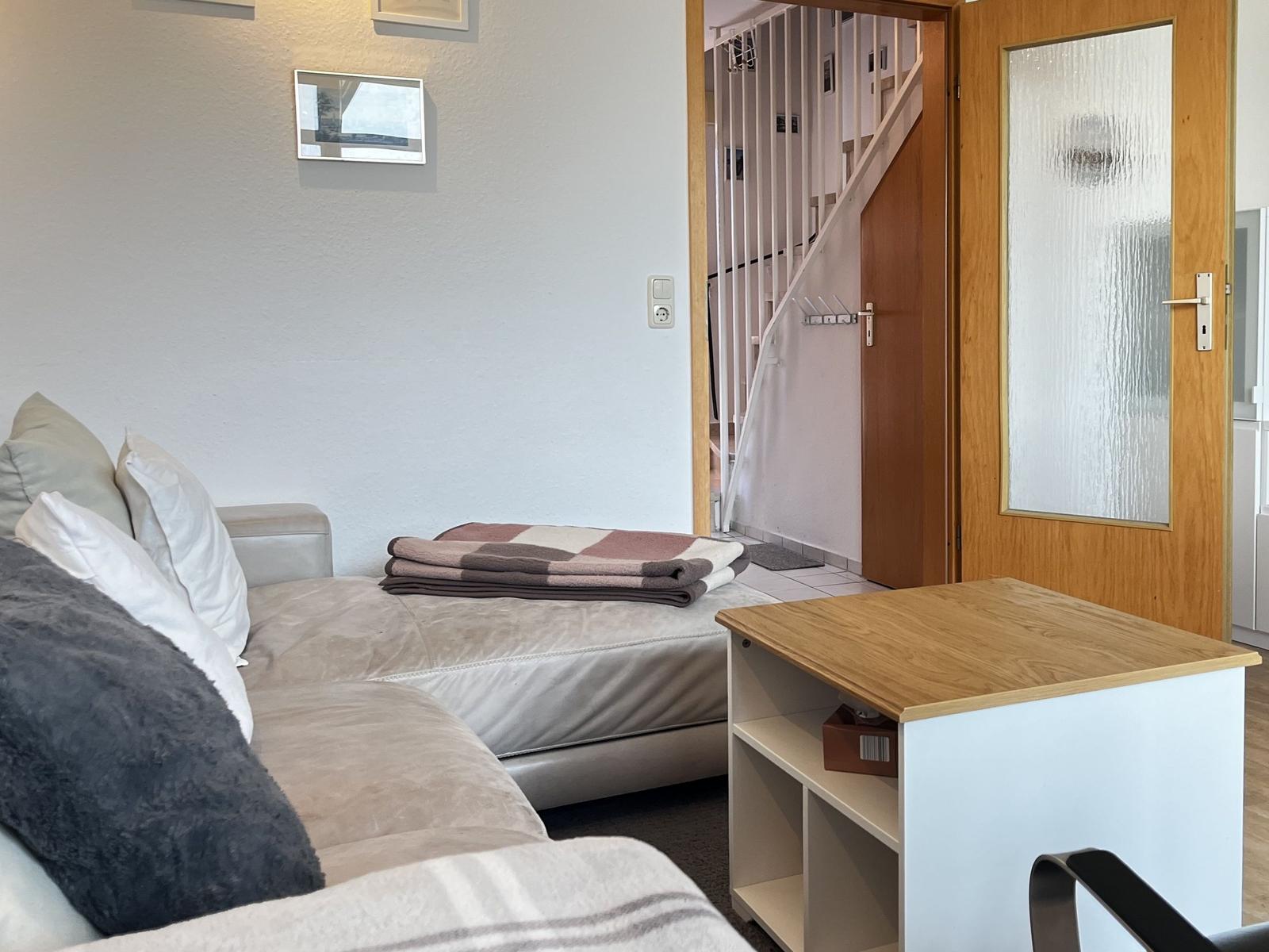 Wohnbereich mit Sofa, Tisch und Blick auf die Treppe.