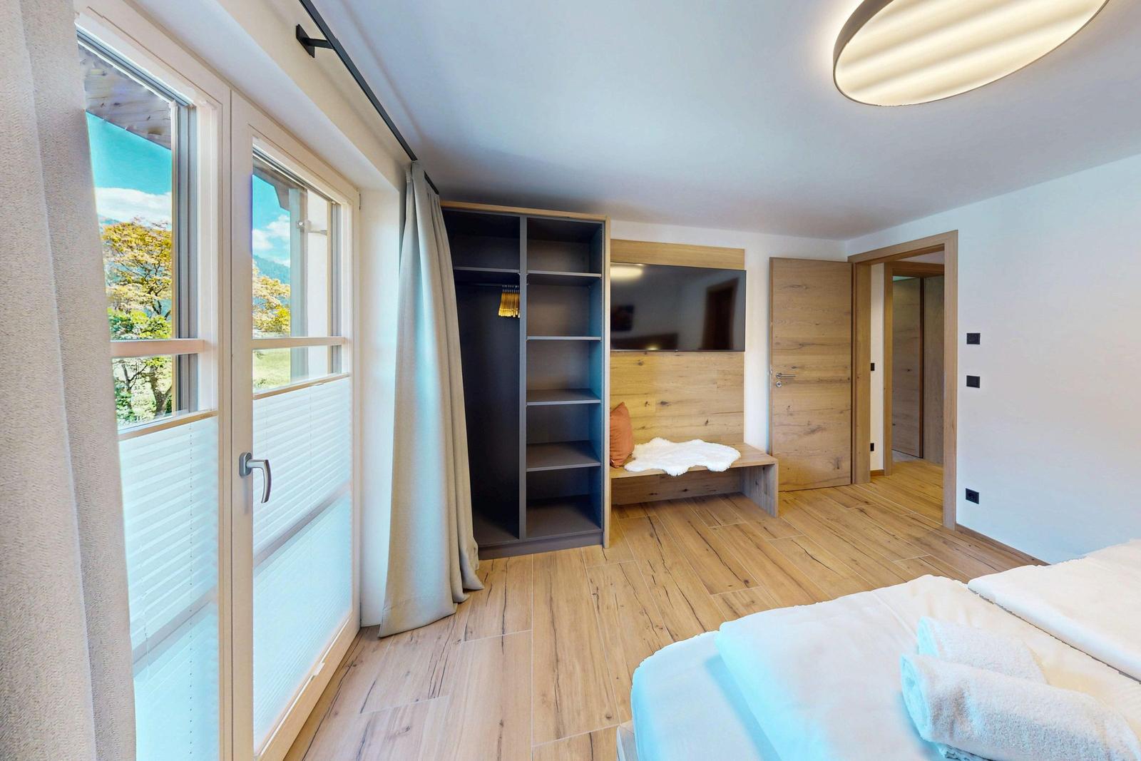 Schlafzimmer mit Bett, Kleiderschrank und Blick auf die Berge.