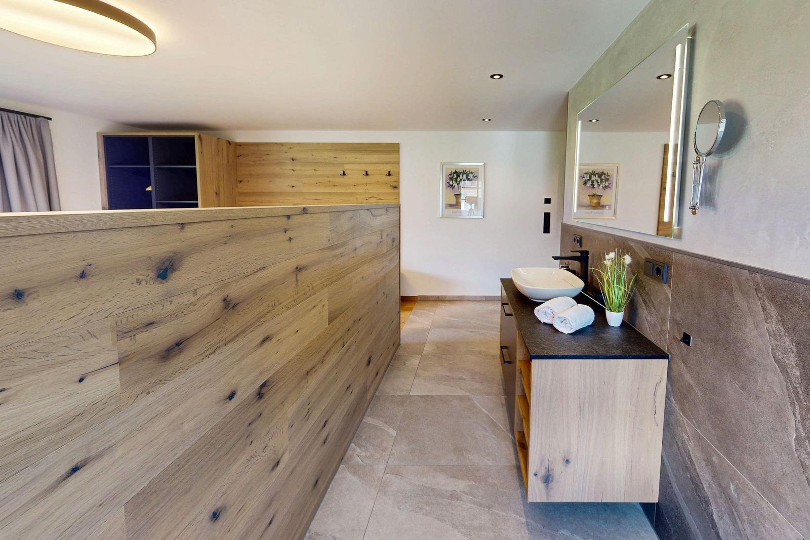 Bad mit Holzwand, Waschtisch und Spiegel. Fliesenboden und moderne Einrichtung.