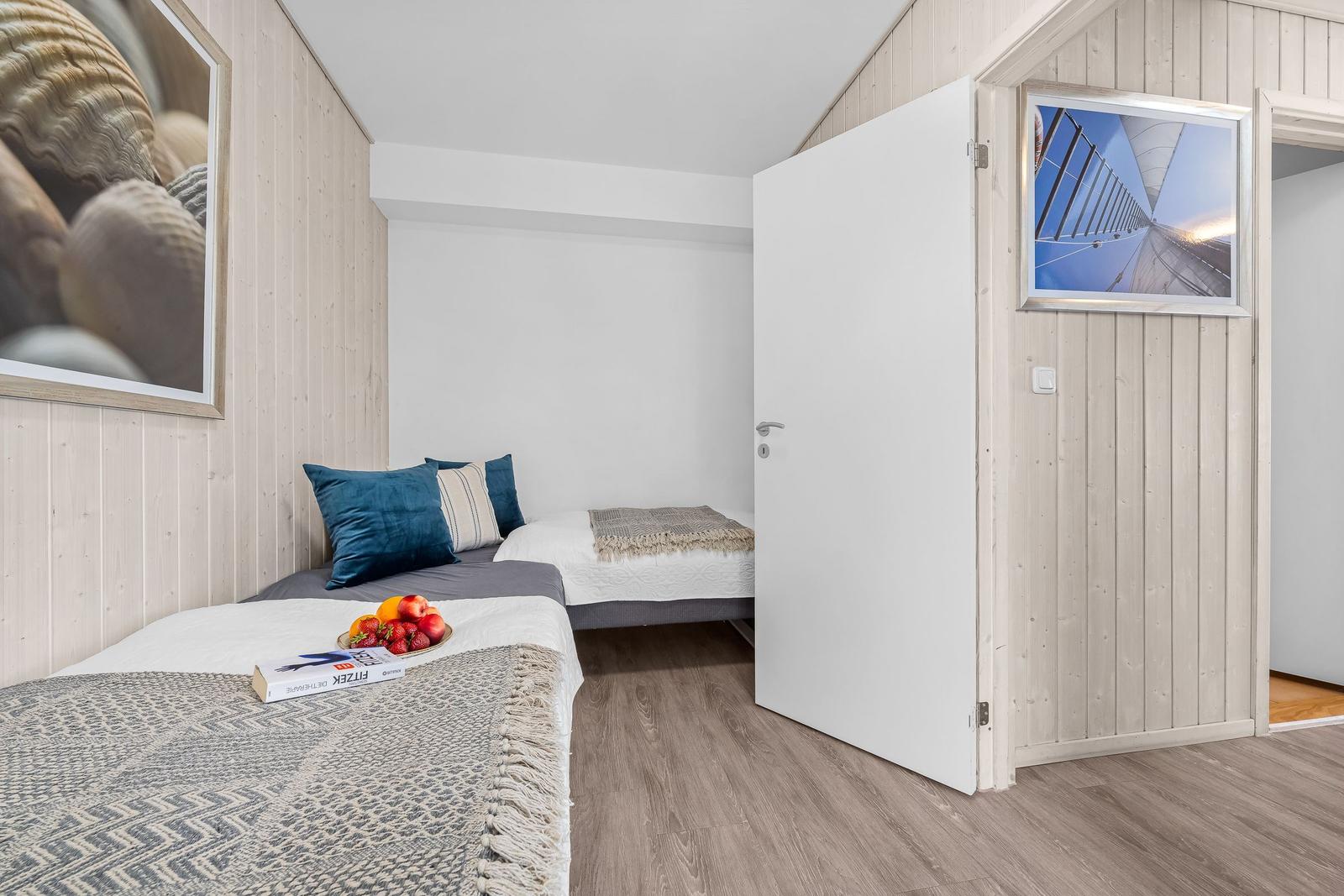 Zimmer mit zwei Betten, Holzwand und Bildern an den Wänden.