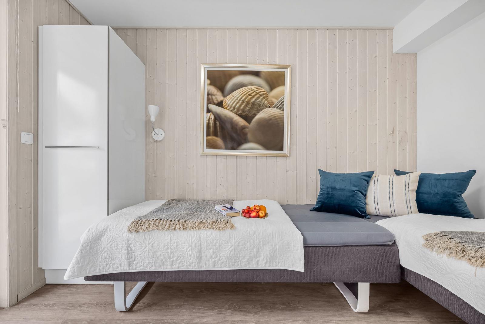 Schlafzimmer mit Bett, Wandbild und Schrank. Decke und Boden sind hell.