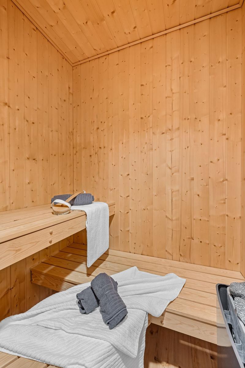 Sauna mit Holzwandverkleidung, Sitzbänken und Handtüchern.