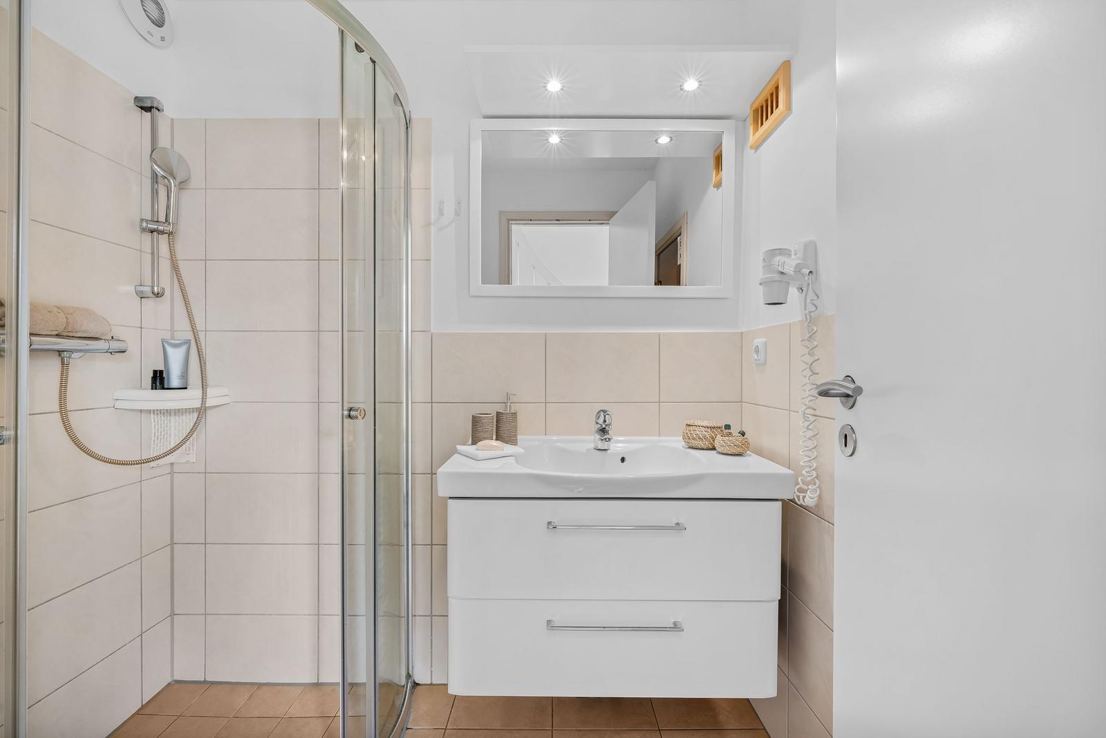 Badezimmer mit Dusche, Waschbecken und Spiegel