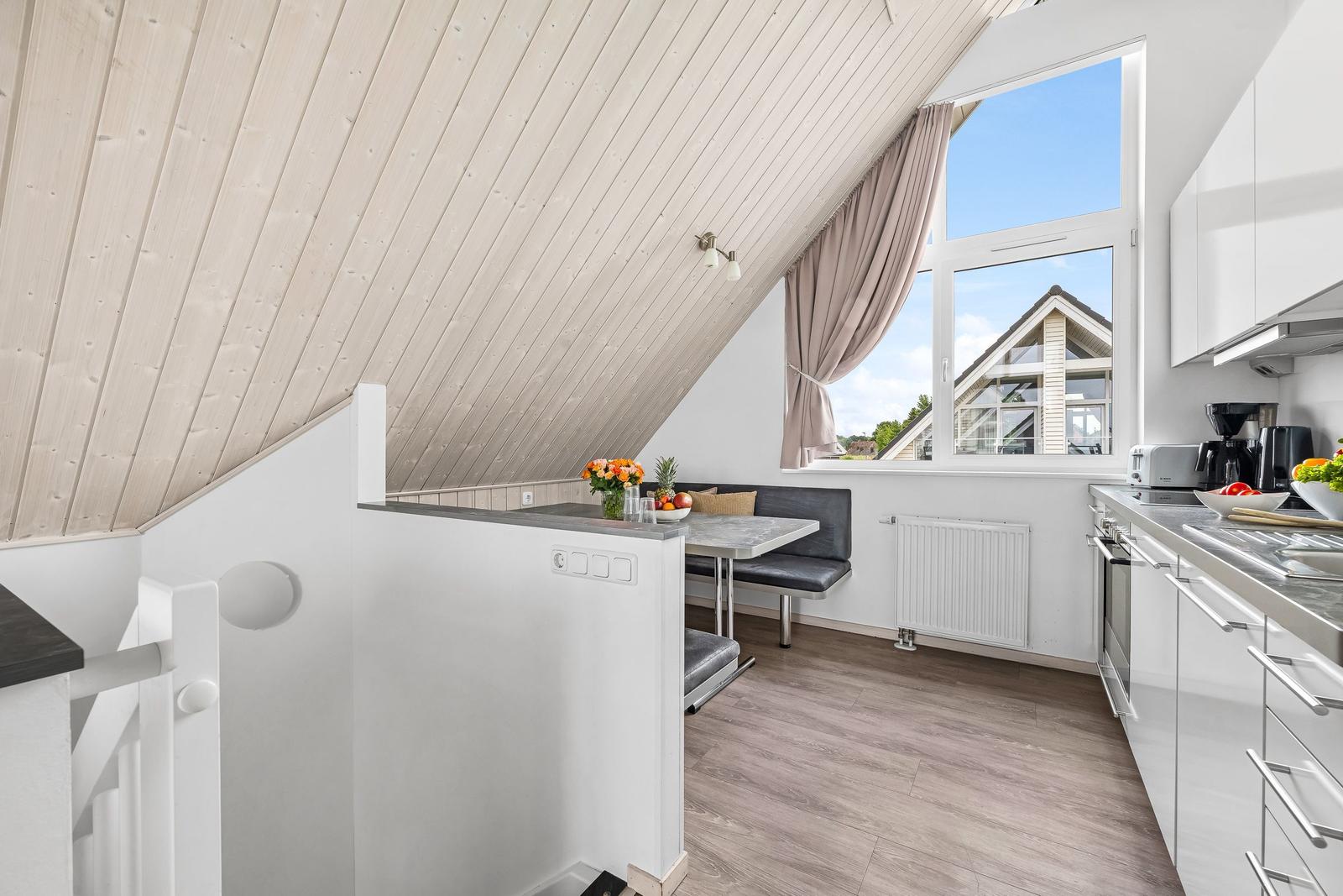 Küche mit Sitzgelegenheit unter Dachschrägen und Blick auf Nachbarhaus