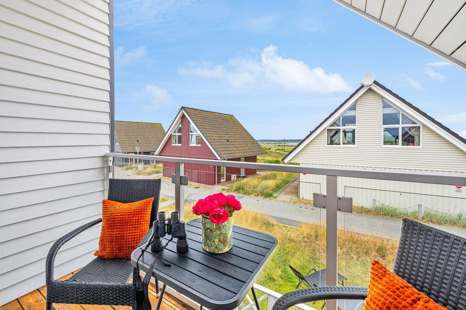 Terrasse mit Tisch, Stühlen und Blick auf Häuser und Landschaft.