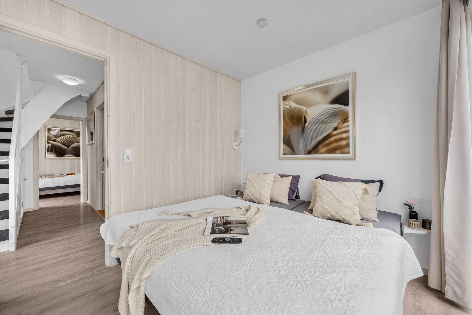 Schlafzimmer mit Bett, Wandbild und Blick in angrenzende Räume.