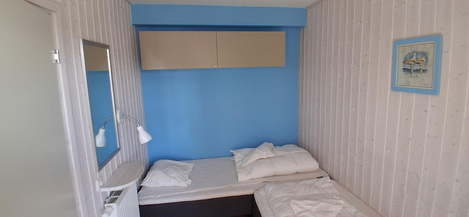 Schlafzimmer mit zwei Betten, blauer Wand und Schrank.
