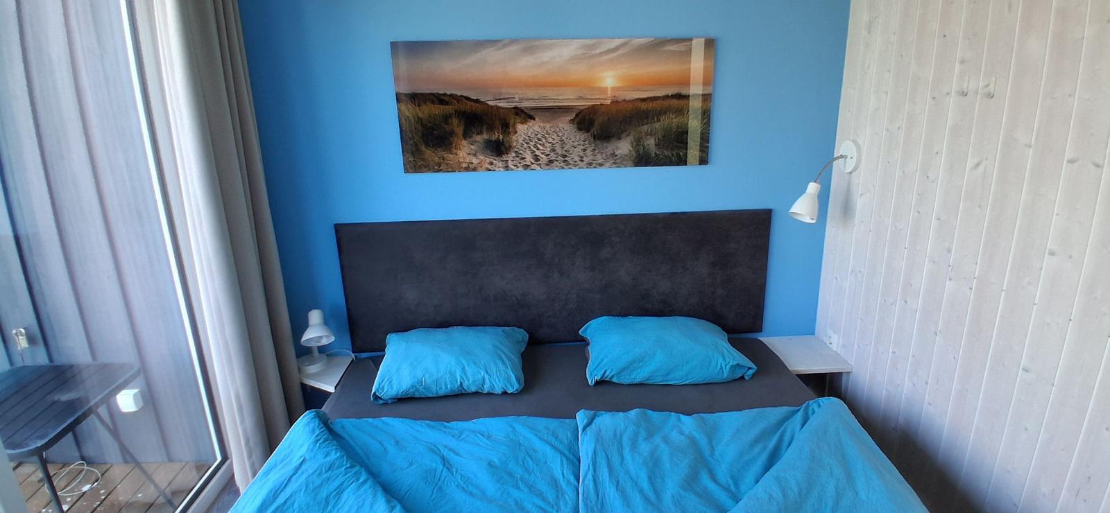 Schlafzimmer mit blauer Wand, Bett und Wandbild
