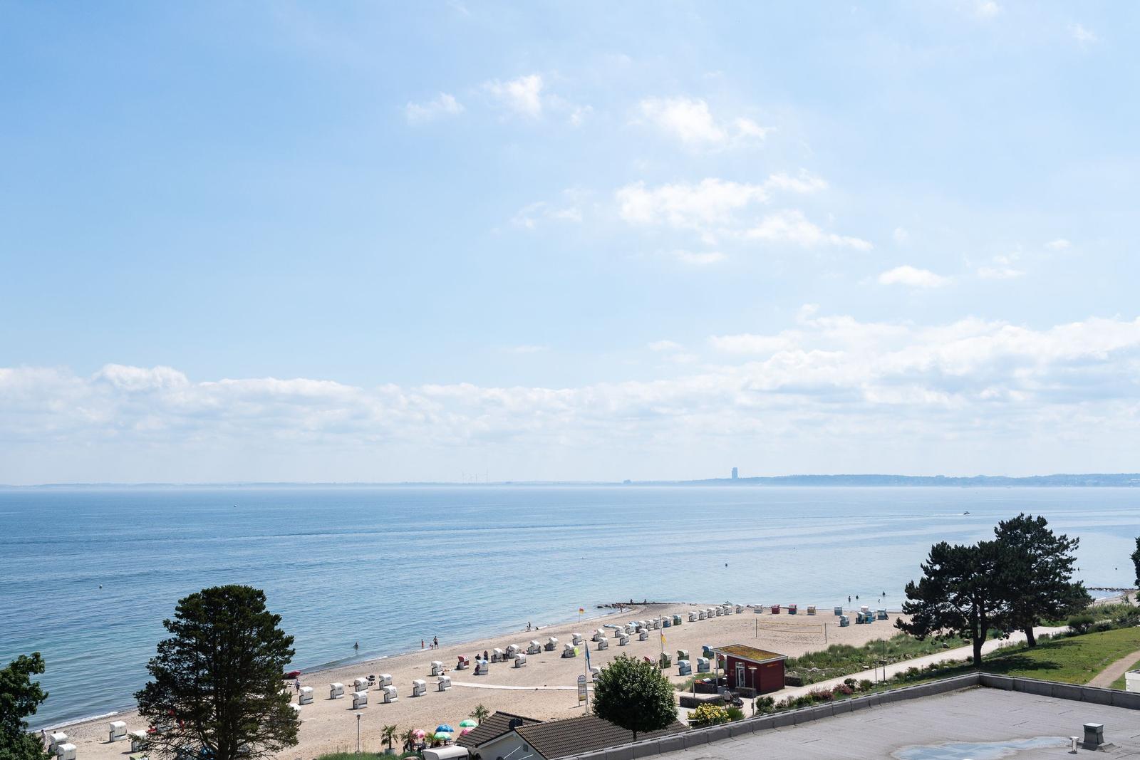 Strand mit Liegestühlen und Blick auf das Meer unter blauem Himmel.