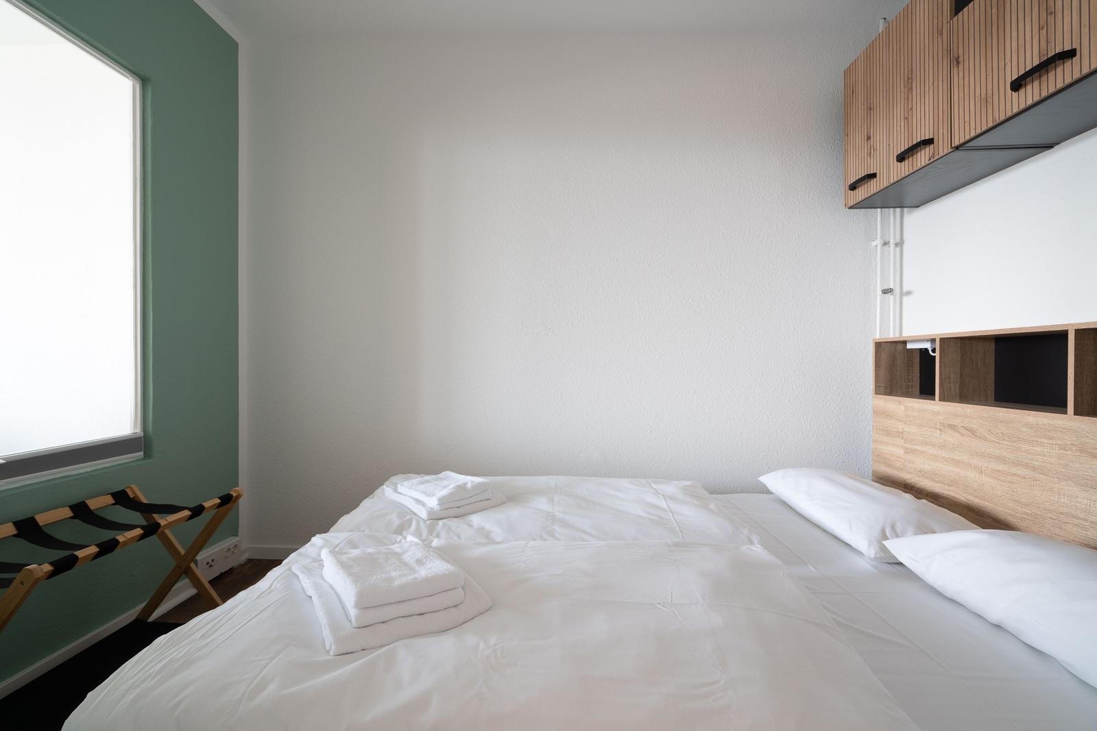 Schlafzimmer mit Bett, weißen Laken und Holzschränken an der Wand.