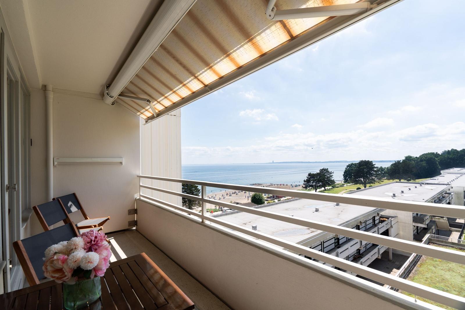Balcony with table and chairs overlooking the sea and beach.