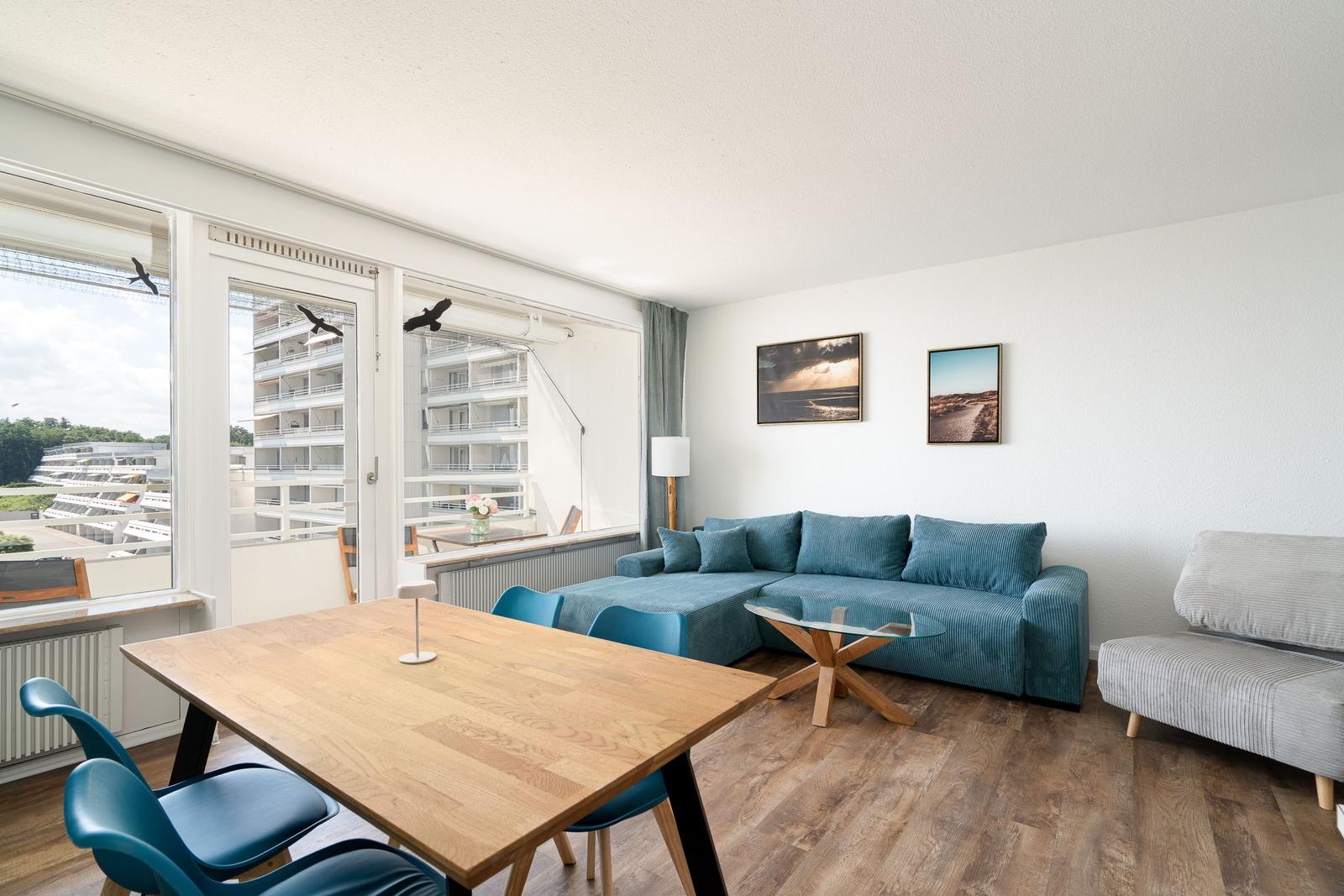 Wohnung mit Essbereich, Sofa und Balkon. Blick auf Gebäude und Himmel.