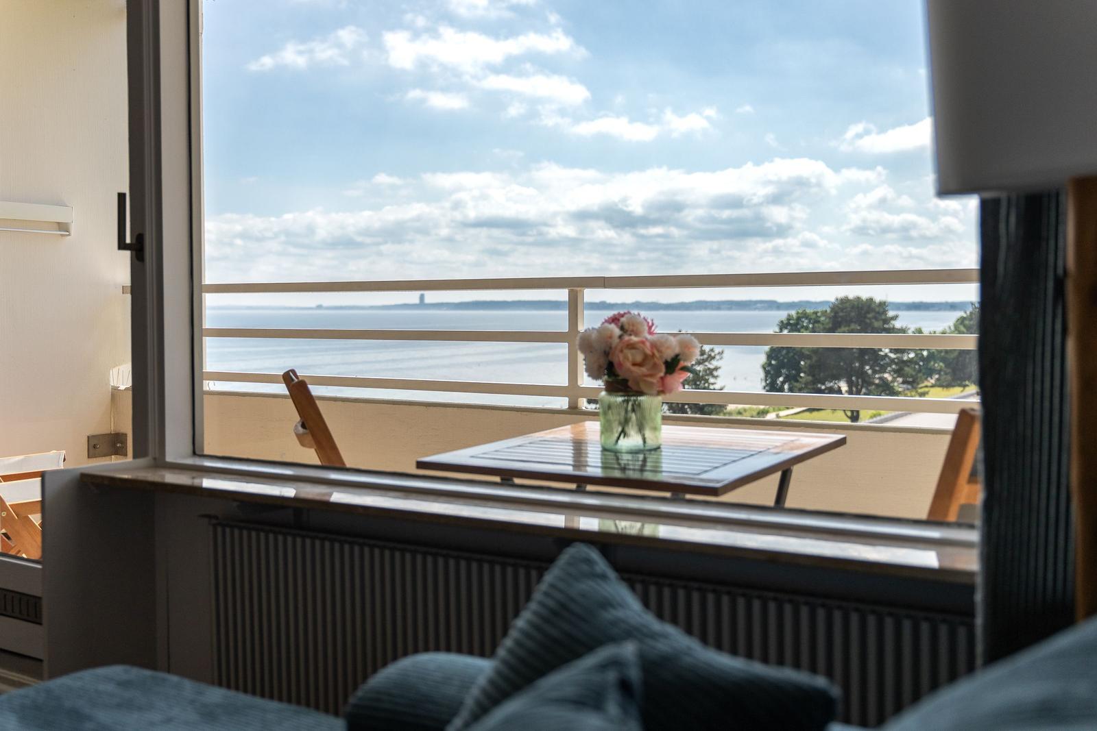 Blick aufs Wasser vom Balkon mit Tisch und Blumen