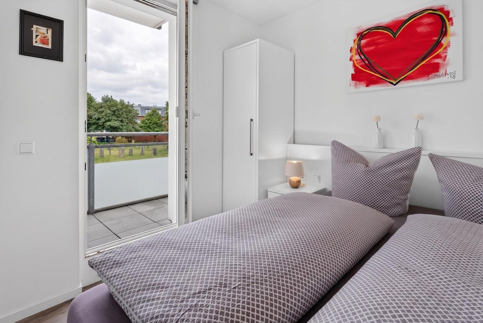 Schlafzimmer mit Doppelbett, Balkon und Wandbild mit Herz.