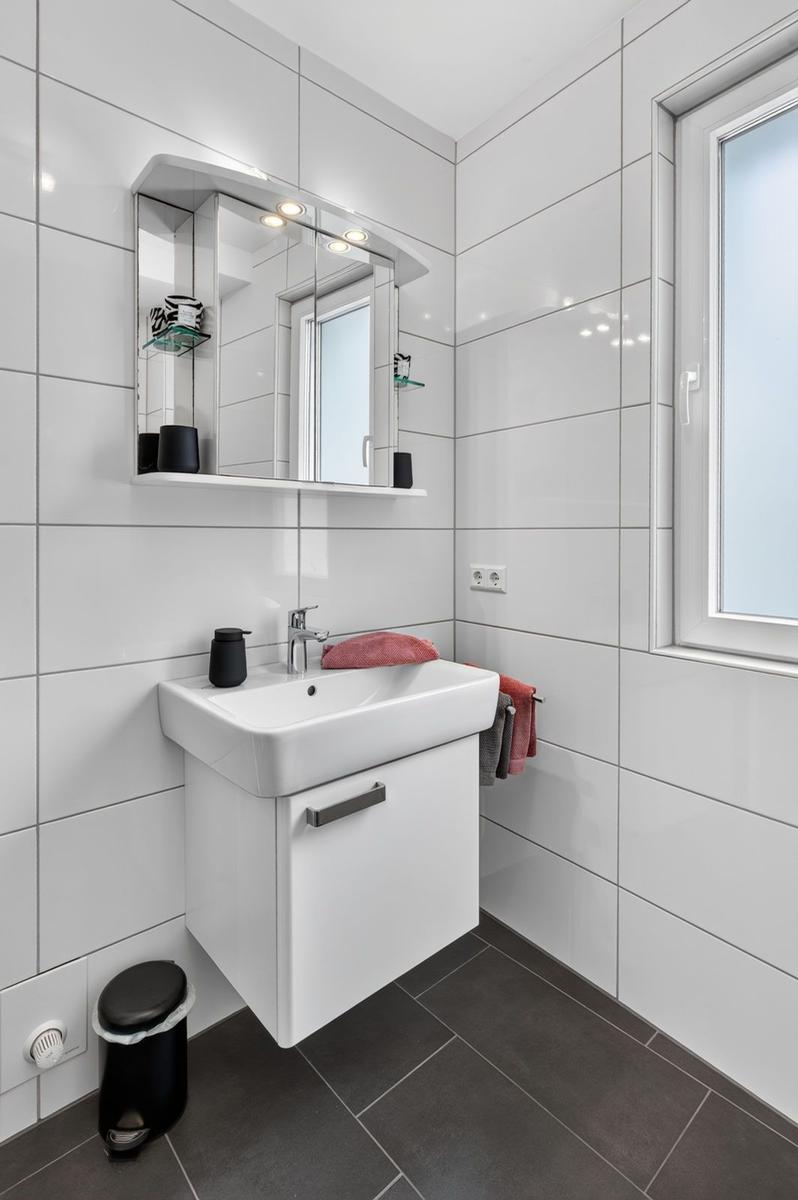 Badezimmer mit Waschbecken, Spiegelschrank und Fenster