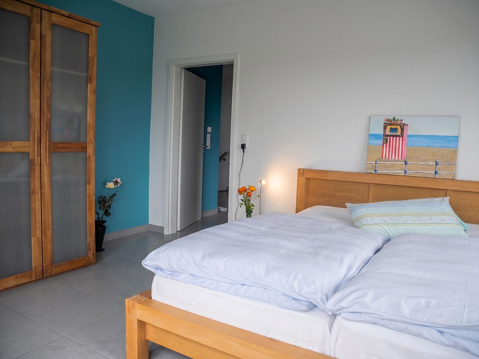 Schlafzimmer mit Doppelbett, Holzschrank und Fenster mit Blick auf Feld.