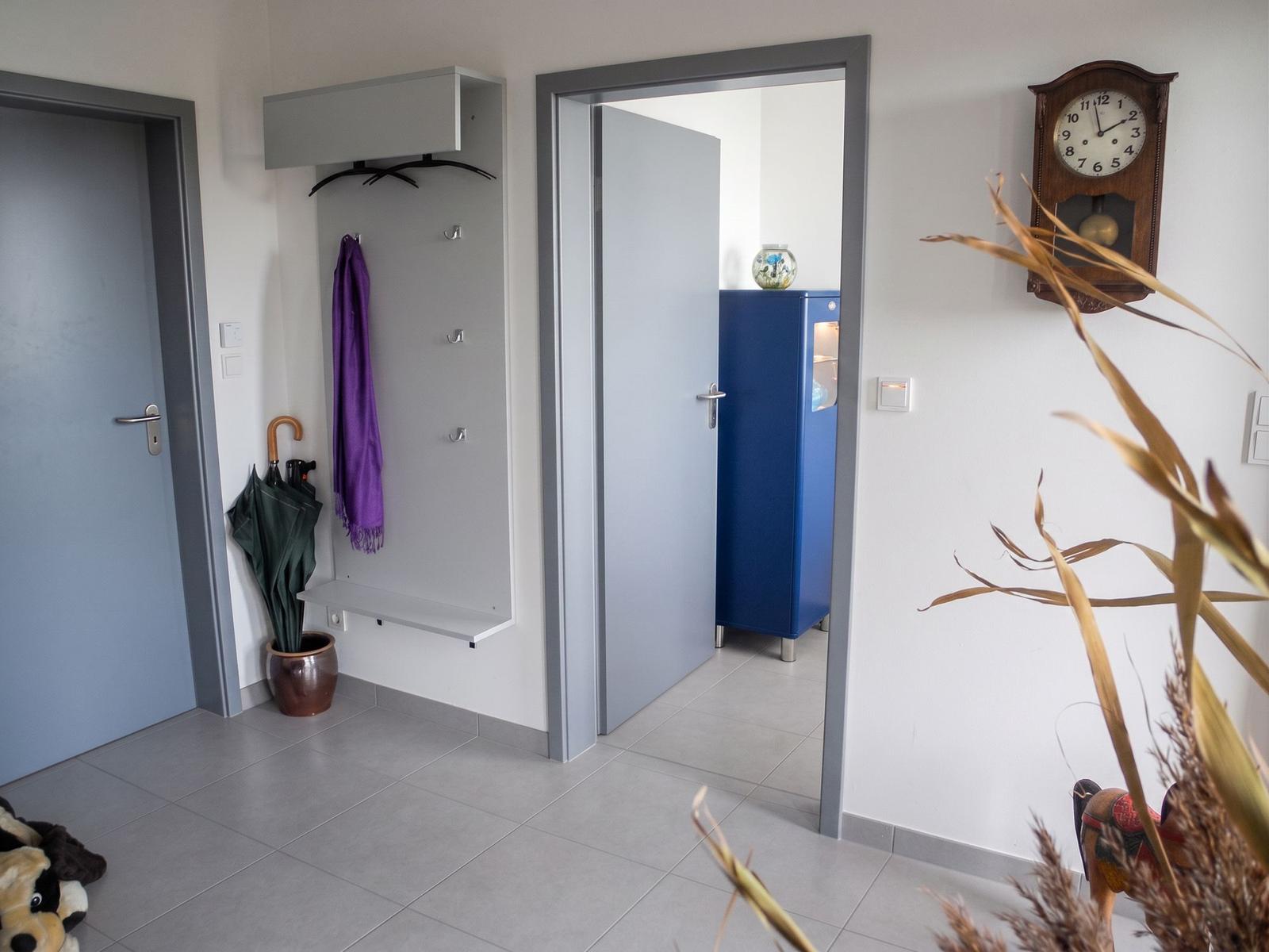 Blauer Schrank mit Fenster zeigt Segelboot und Leuchtturm. Oben steht eine Glasvase.