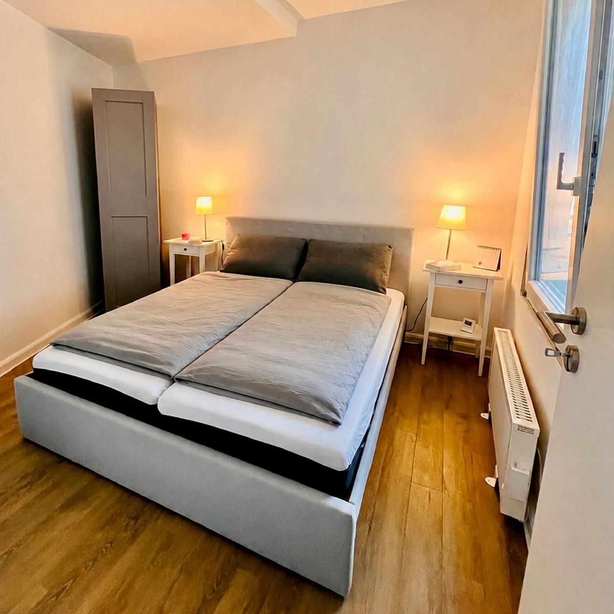 Schlafzimmer mit Doppelbett, zwei Nachttischen und einem Fenster.