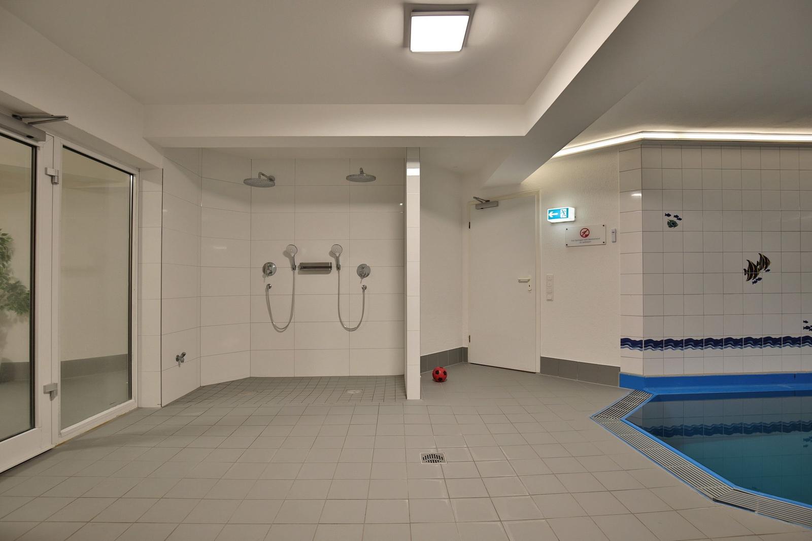 Indirekter Blick auf die Dusche und den Poolbereich mit blauem Rand.