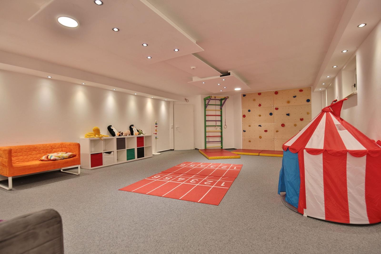Kinderzimmer mit Kletterwand, Zelt und Spielmatte.