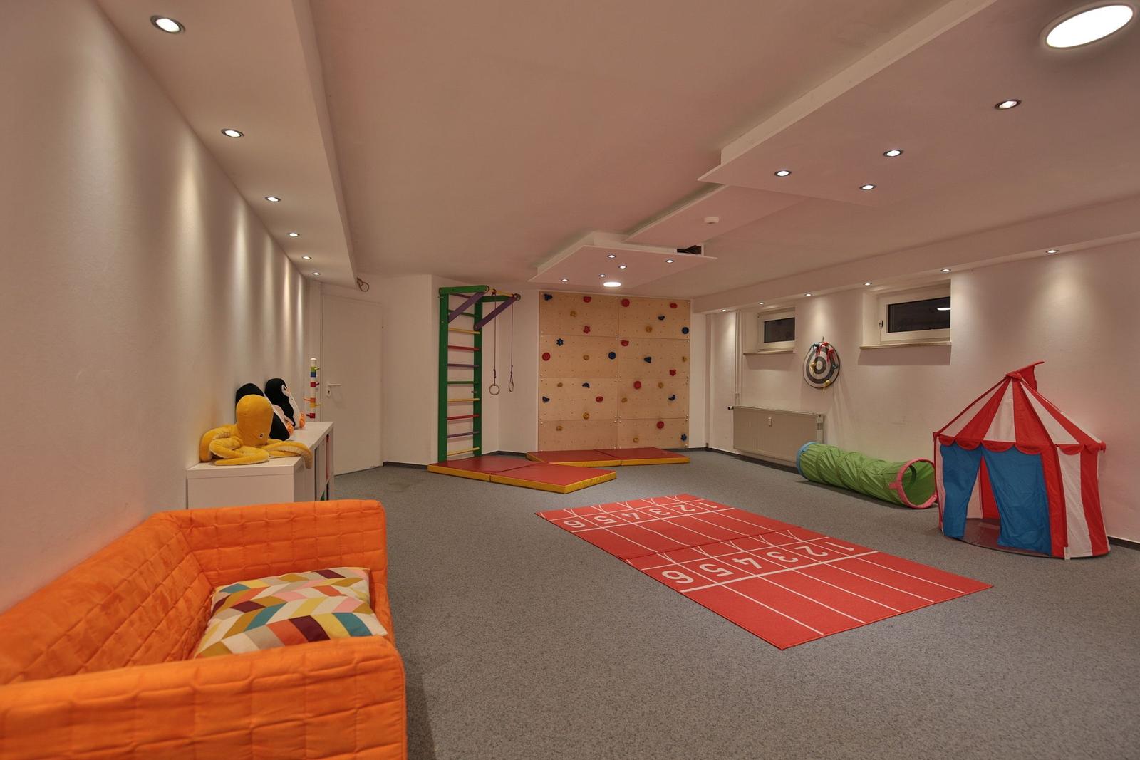 Kinderzimmer mit Kletterwand, Laufrinne, Zelt und Spielzeug.
