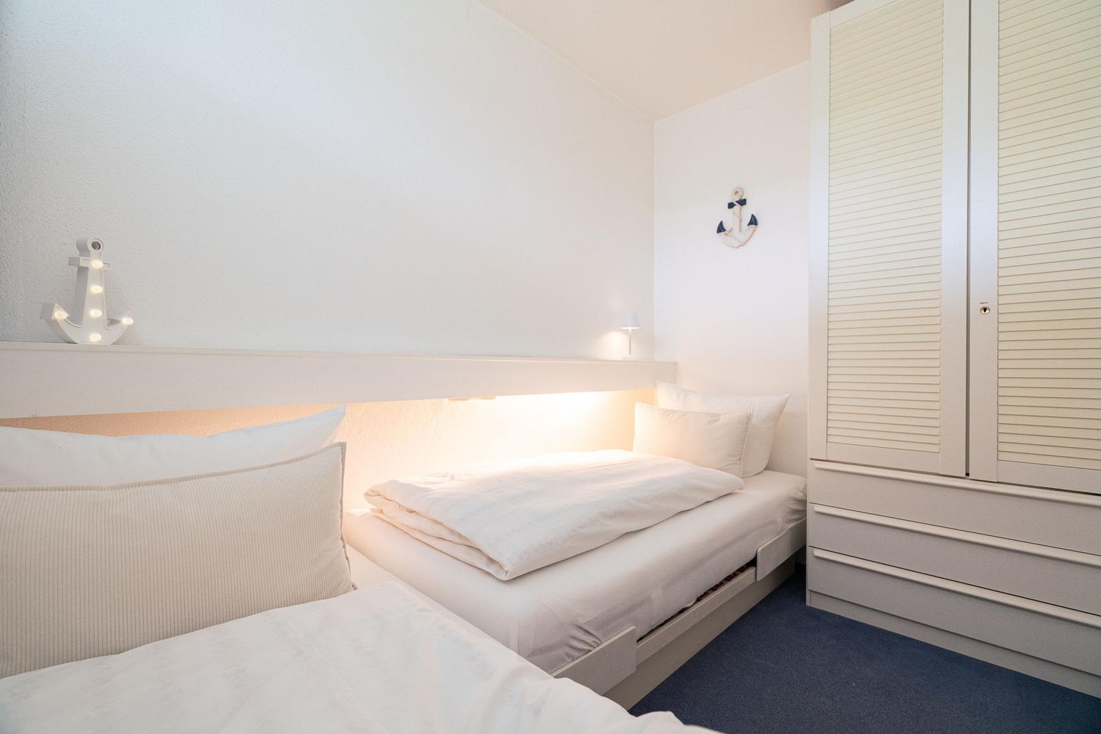 Zimmer mit zwei Betten, Schrank und Anker-Dekoration an den Wänden.